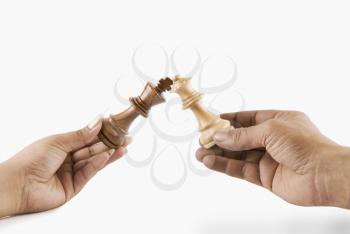 Close-up of a man and woman's hands holding chess king and queen