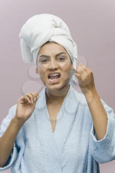 Portrait of a young woman flossing her teeth