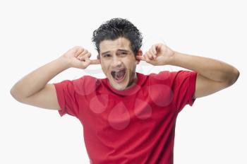 Portrait of a man screaming with his fingers in ears