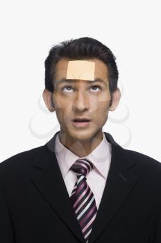 Businessman looking at a sticky note on his forehead