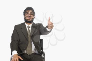 Portrait of a businessman showing thumbs up with his face covered with phone cord