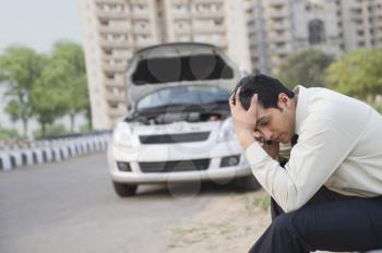 Worried businessman talking on a mobile phone after his vehicle breakdown