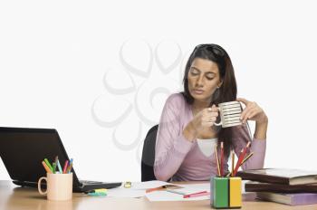 Female fashion designer working in an office and drinking coffee