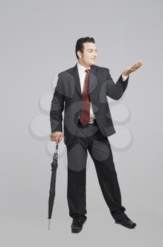 Businessman holding an umbrella and checking for rain