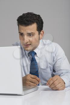 Businessman looking worried while using a laptop