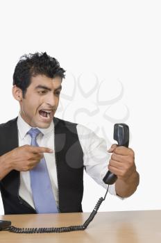 Businessman shouting at a telephone receiver