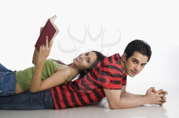 Woman lying on a man's back and holding a book