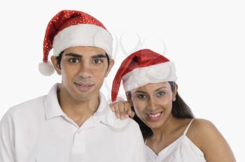 Portrait of a couple wearing Santa hats and smiling