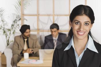 Businesswoman smiling with her colleagues in the background