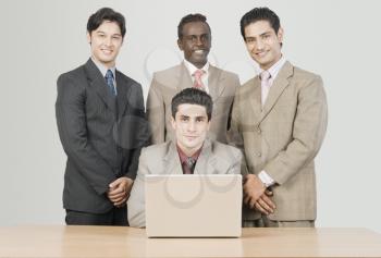 Portrait of four businessmen in front of a laptop