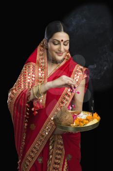 Woman in red mekhla holding religious offering