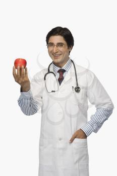Portrait of a doctor holding an apple and smiling