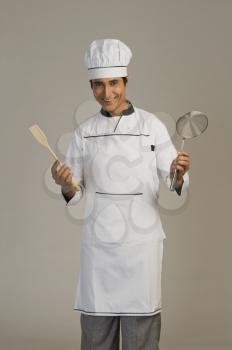 Portrait of a chef holding a sieve and a wooden spoon