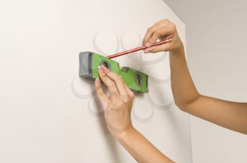Woman using a spirit level and marking on the wall