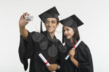 Couple in graduation gown taking a picture of themselves