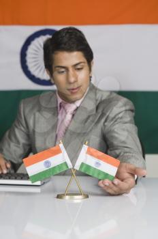 Close-up of a businessman touching Indian flags on the desk in front of him