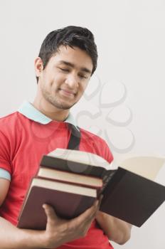Man leaning against a wall and reading a book