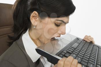 Businesswoman biting a laptop