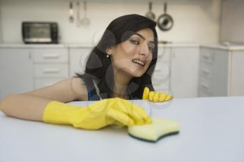 Woman cleaning a kitchen counter with a sponge