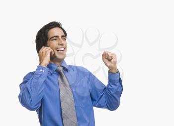 Businessman raising fist while talking on a mobile phone