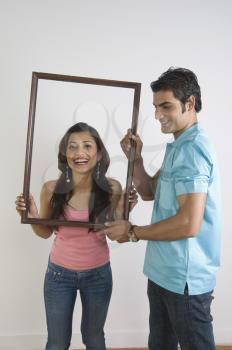 Man holding a picture frame in front of a woman