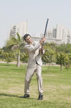 Businessman playing hockey in a park