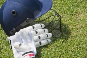 Cricket helmet and batting gloves in a field