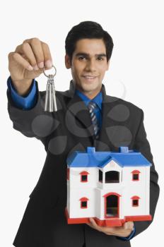 Real estate agent holding house keys and a model home