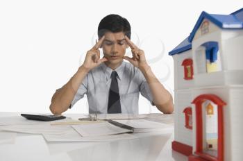 Real estate with head in hands sitting near a model home