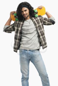 Man holding a skateboard on his shoulders