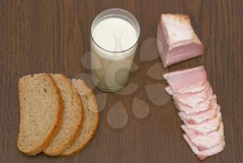 Milk in a glass, the cut bread and bacon.                   