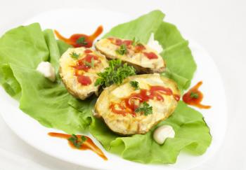 Baked potatoes filled with ham, eggs and cheese, decorated with parsley, ketchup, mayonnaise and lettuce