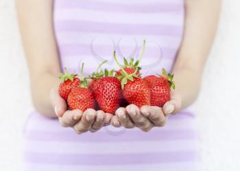 Girl hold fresh strawberries. Shallow DOF, focus on strawberries.
