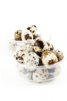 Two plastic bowls with many quail eggs on white background