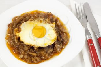 Delicious stew with baked onion, egg and sausages. View from top.