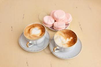 Two cups of coffee and macaroons on a vintage table.