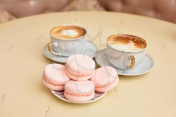 Macaroons and two cups of coffee on a vintage table.