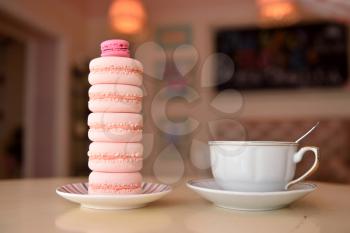 A tower made of macaroons and a cup of coffee on a beautiful vintage table.