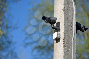 CCTV camera on a concrete pillar against a blue sky