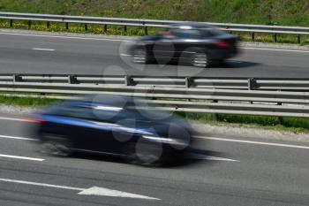 A blue cars at high speed rides along the road, blurred in motion