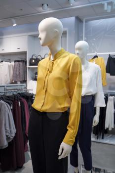 Female mannequin in a women's clothing store. Mannequin in a yellow blouse and trousers