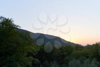 Evening landscape with mountains overgrown with trees against a sunset. Beautiful mountains around Geledzhik