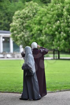 Two women refugees walking in hijabs in the European park. Germany