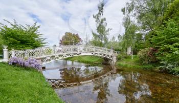 A beautiful white wrought iron bridge over a river in the European city of Baden Baden. Landscape with a bridge over a river