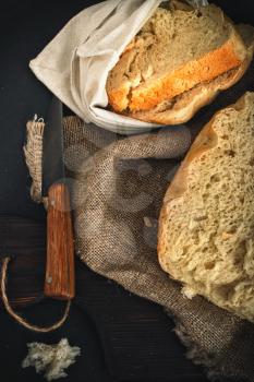 Freshly baked bread lies on a cutting board and on burlap.