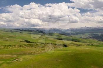 Mountain peaks and grassland are under white clouds. Shot in Xinjiang, China.