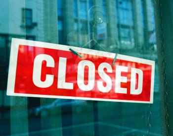 Red closed sign in a shop windows with reflections on glass