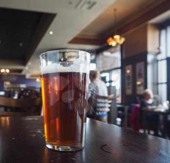 A pint of British ale beer in a pub, selective focus on glass with blurred background
