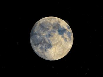 Full moon seen with an astronomical telescope, with starry sky