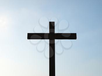 Dark wooden cross over a blue sky background